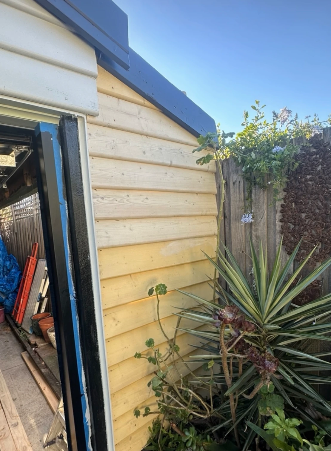 Completed timber weatherboards fitted to the exterior gable beside a garden